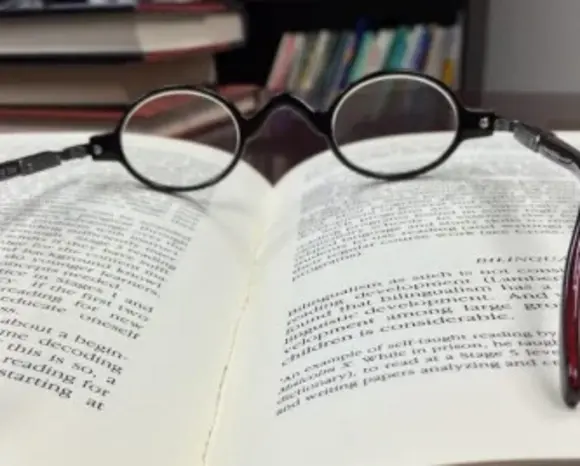 Brille liegt auf Buch.