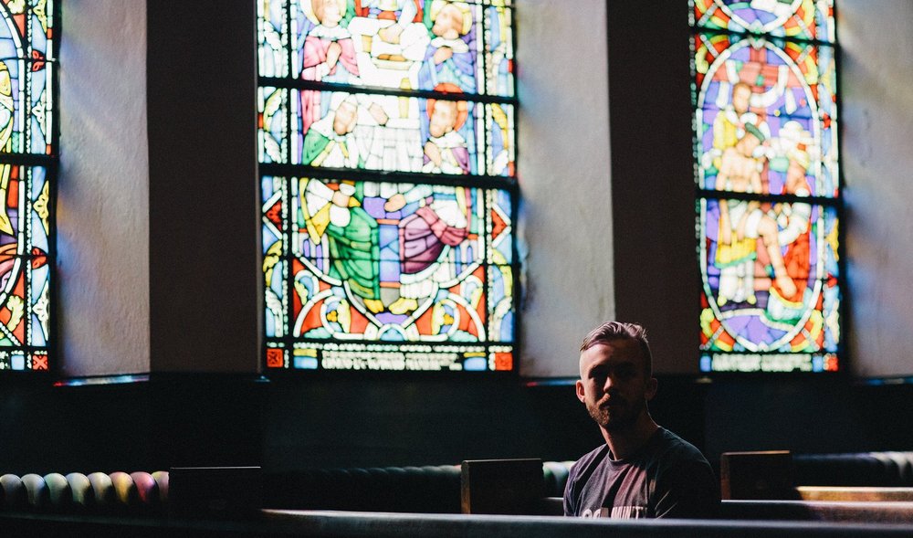 Sitzender junger Mann in einer dunklen Kirche