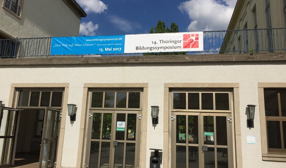 Blick auf den Eingang eines Gebäudes der Universität Erfurt mit einem Banner zum 14. Thüringer Bildungssymposium in Erfurt