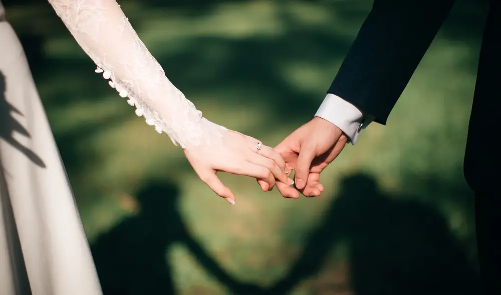 Braut und Bräutigam halten einander die Hand (Symbolbild Familie)