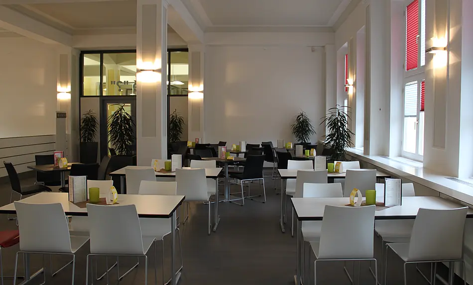 Einblick ins Cafe Hörsaal 7, leere Tische und Stühle, Pflanzen und rote Rolläden, Lichtspiele