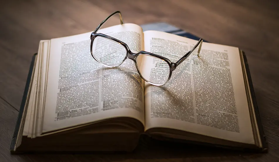 [Translate to English:] Brille auf aufgeschlagenem Buch