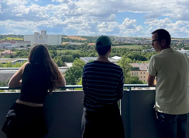 Three people are looking out over the campus from the high-rise building
