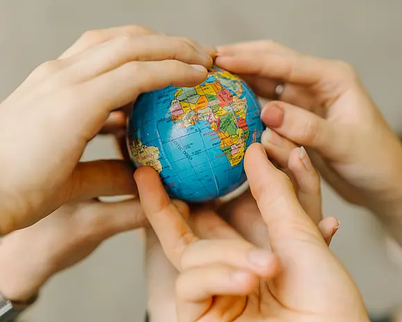 mehrere Hände halten einen Globus