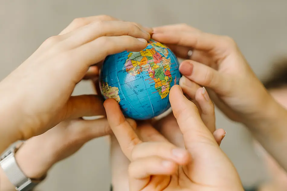 mehrere Hände halten einen Globus