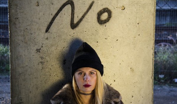 Frau vor einer Wand, auf der das Wort "No" steht