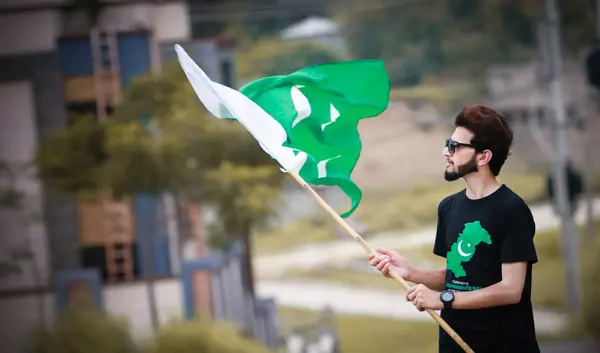 Ein Mann schwenkt eine Fahne in pakistanischen Nationalfarben
