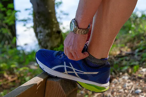 Ein Mann bindet sich seinen Turnschuh zu.