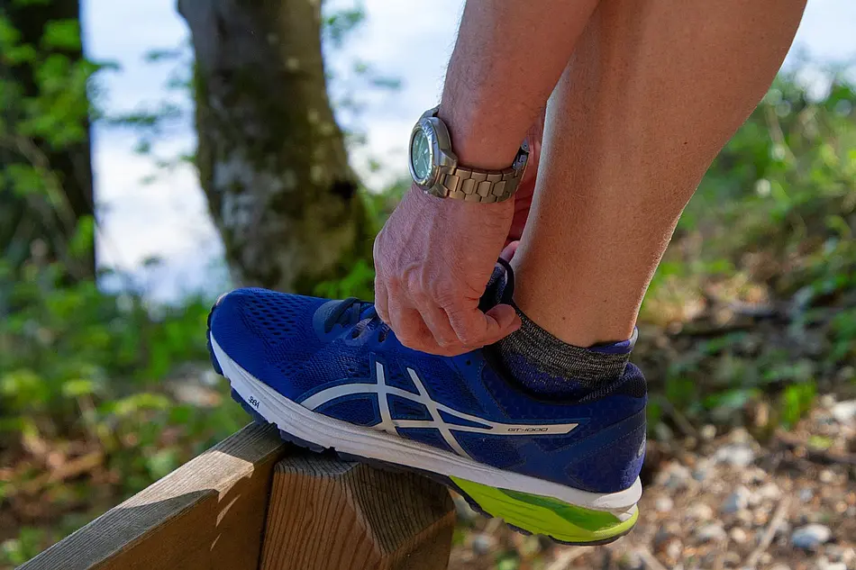 Ein Mann bindet sich seinen Turnschuh zu.