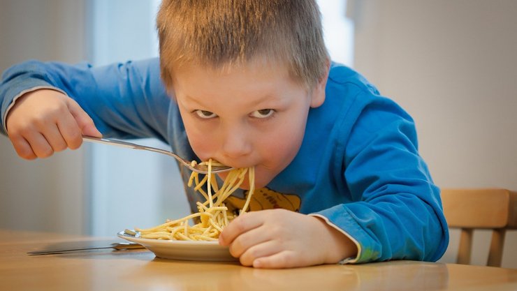 [Translate to English:] Ein Junge isst Spaghetti