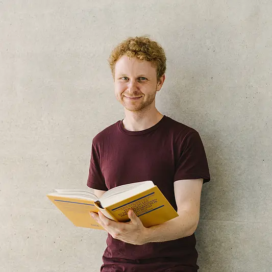 Student mit Buch lächelt