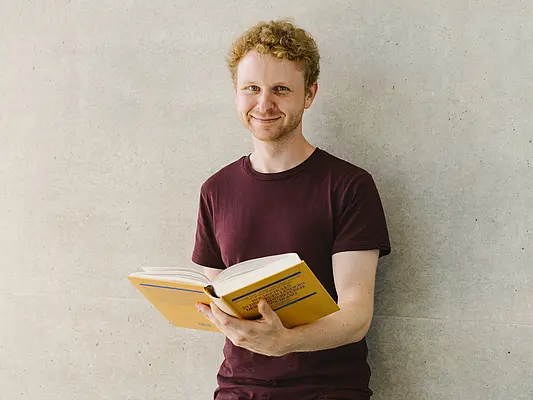 Student mit Buch lächelt