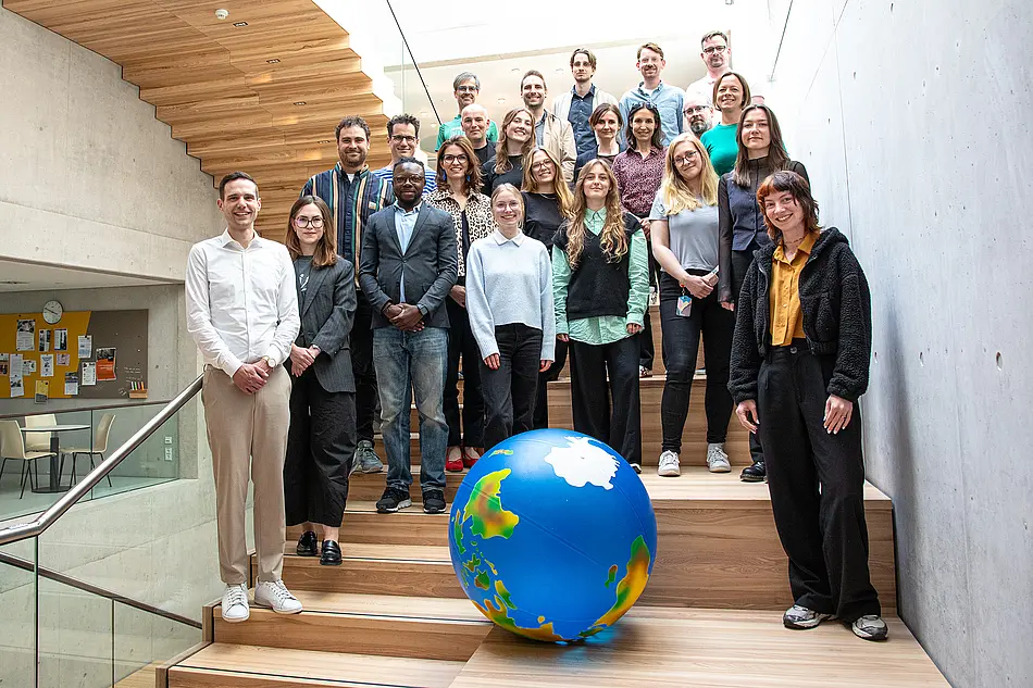 Gruppenbild IPB: Viele Menschen auf einer Treppe, schauen in Kamera, großer Erdball im Vordergrund