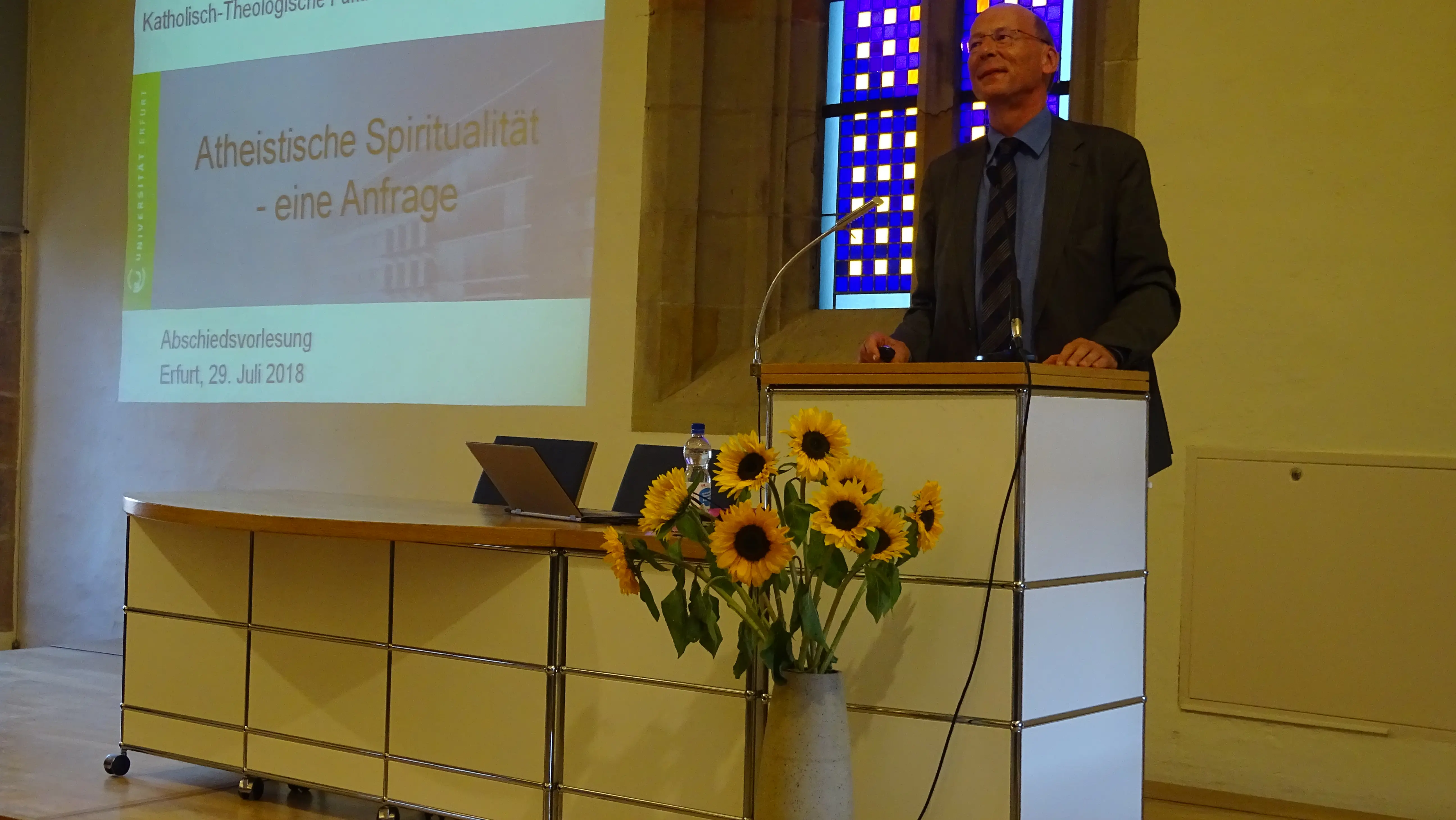 Prof. Dr. Eberhard Tiefensee am Rednerpult während seiner Abschiedsvorlesung mit Präsentationsfläche "Atheistische Spiritualität - eine Anfrage"
