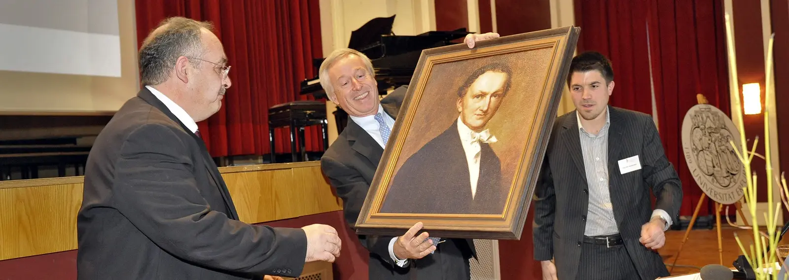 Franz Markus Haniel holding a framed painting of Franz Haniel