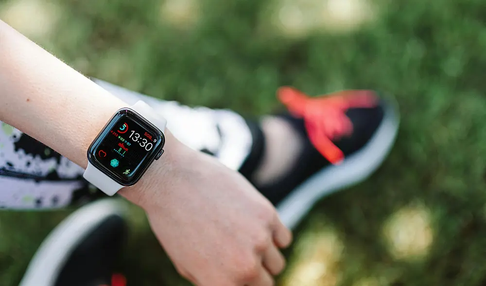 Bildausschnitte: Eine Frau in Laufkleidung schaut auf den Stand ihrer Smartwatch