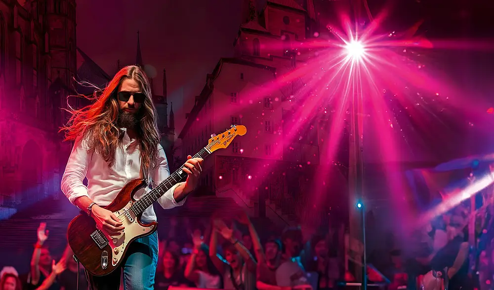 Ein Rockstar, der wie Jesus aussieht spielt auf einer Bühne vor den Erfurter Domstufen Gitarre und wird von der Menge bejubelt.