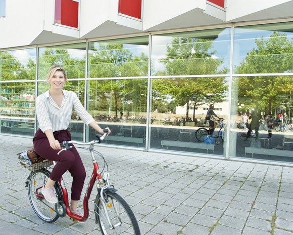 Studentin auf dem Fahrrad vor der Bibliothek der Uni Erfurt