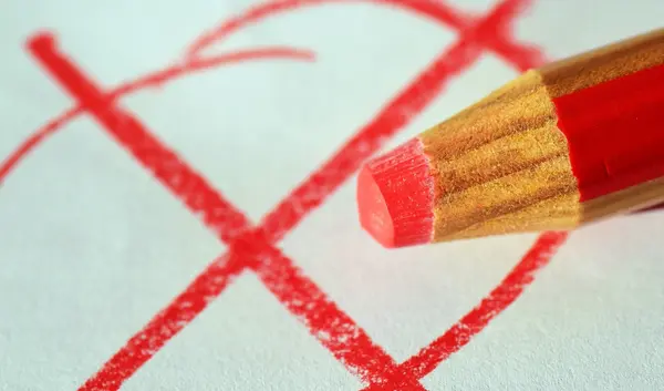 Ein roter Stift setzt ein Kreuz auf ein Blatt Papier