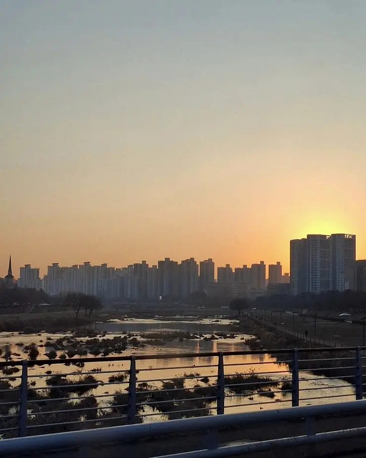 Blick von einer Straße auf das Uni-Viertel Yuseong-gu und den gleichnamigen Fluss in Daejeon mit Abendsonne und vielen Hochhäusern