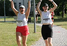 zwei Läuferinnen, die ihre Hände in die Luft strecken und lachen