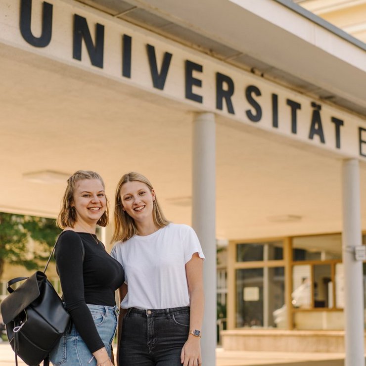 Zwei Studierende vor dem Haupteingang der Uni Erfurt