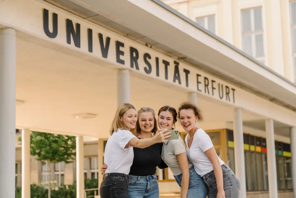 student in front of the main entrance of the University of Erfurt