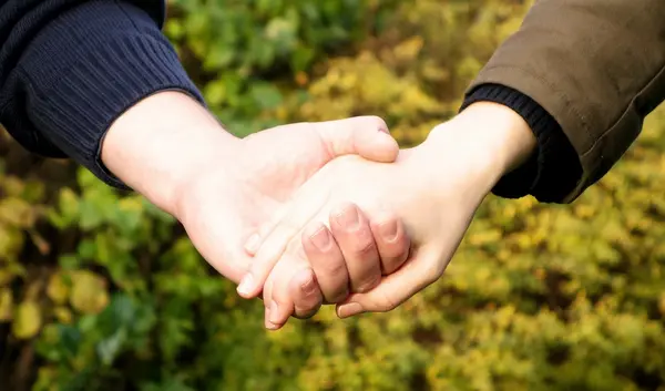 Zwei Menschen halten sich bei den Händen