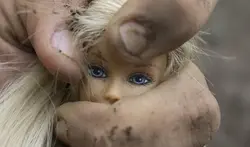 Der Kopf einer Barbiepuppe wird in der Hand eines Manns zerdrückt