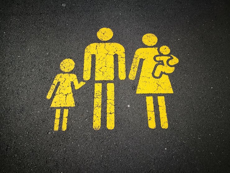 Bright yello graffito on tarmac, showing icons of a man, woman and two small children