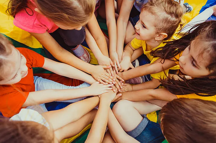Kinder strecken ihre Hände zusammen in die Mitte