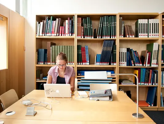 Eine Studentin arbeitet an einem Arbeitsplatz in der Universitätsbibliothek der Universität Erfurt