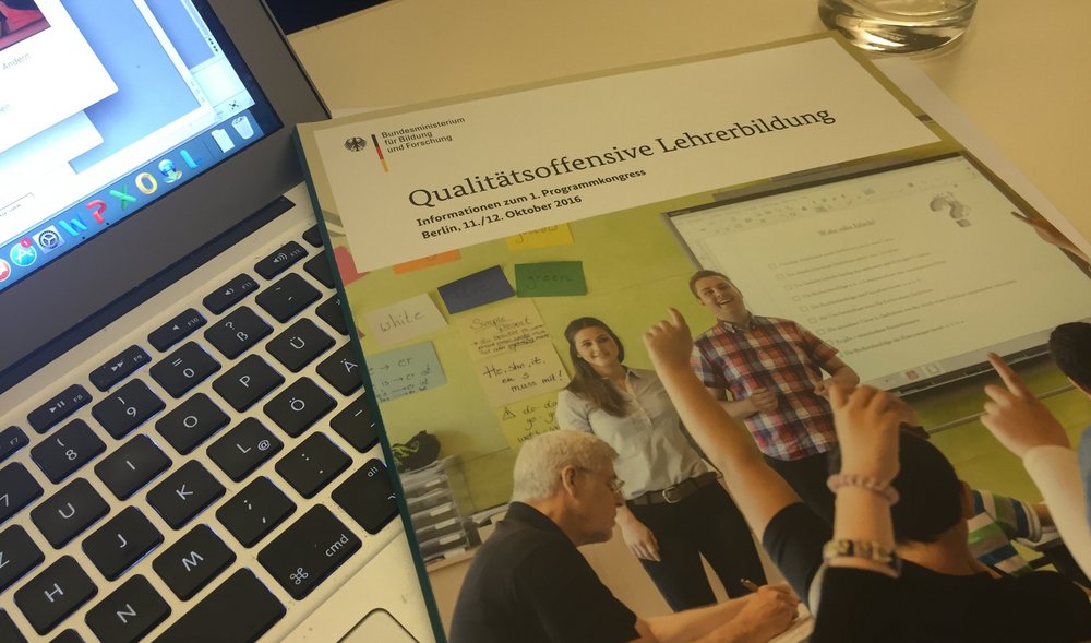 Auf einem geöffneten Laptop liegt eine Broschüre des Bundesministeriums für Bildung und Forschung "Qualitätsoffensive Lehrer:innenbildung"