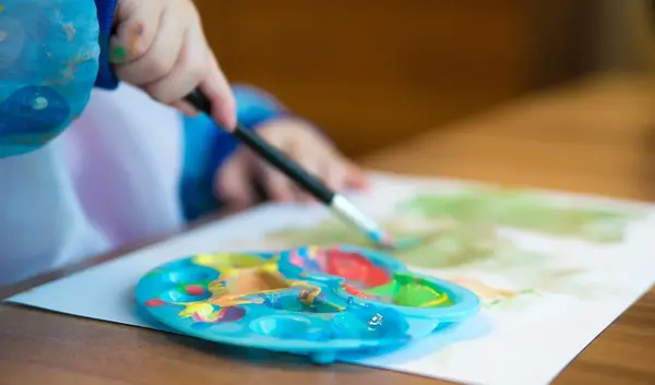 Kind malt mit Farbpalette