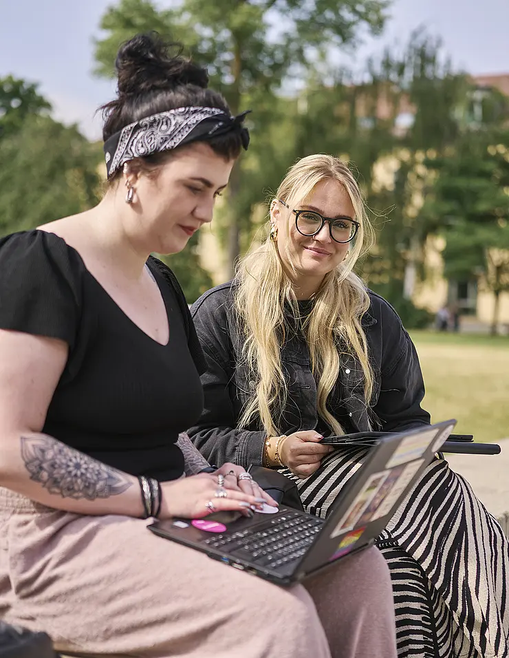 Studentinnen auf dem Campus mit Laptop