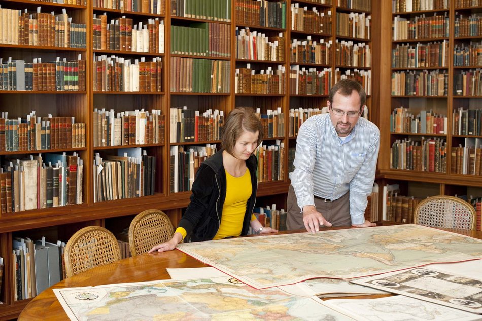 Mitarbeiter der Sammlung Perthes mit einem Kind über eine Karte gebeugt, Forschungsbibliothek Gotha der Universität Erfurt