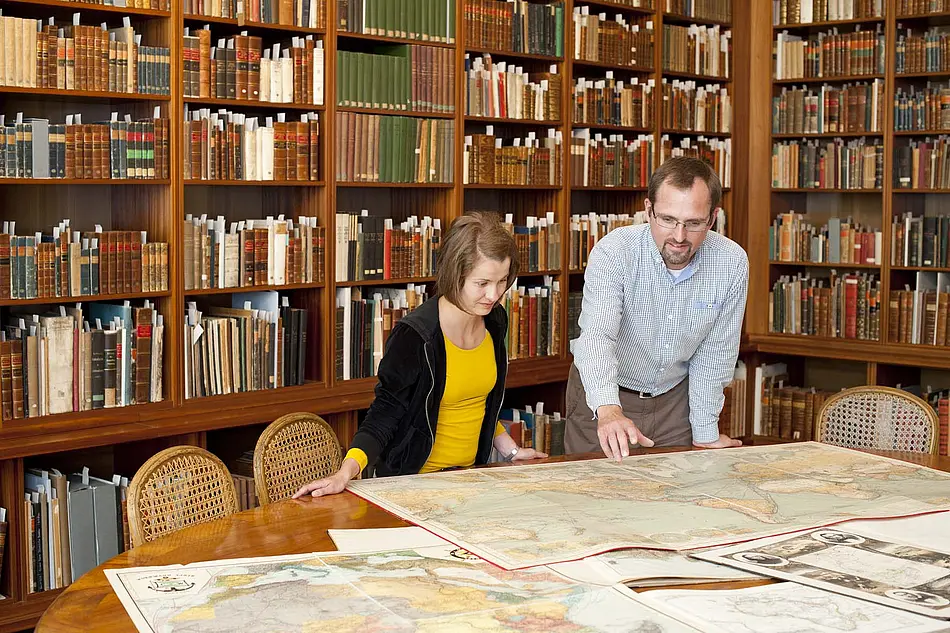Mitarbeiter der Sammlung Perthes mit einem Kind über eine Karte gebeugt, Forschungsbibliothek Gotha der Universität Erfurt