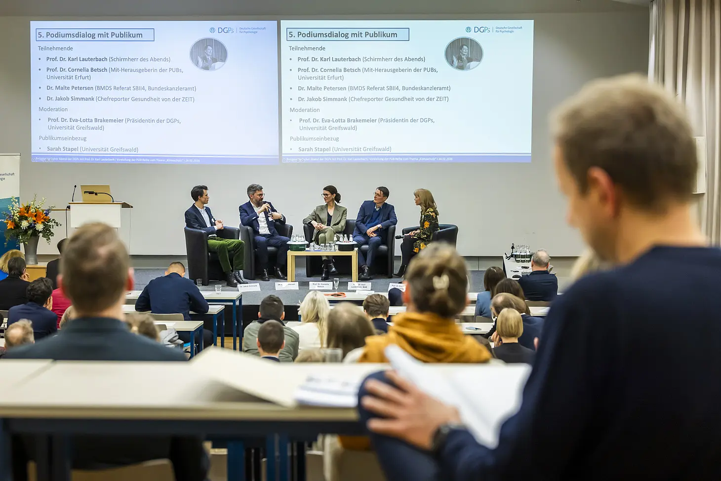 Menschen sitzen auf einem Panel auf einer Bühne