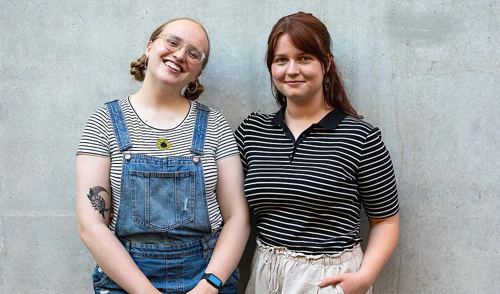 Weronika und Alicia lächelnd vor einer grauen Betonwand