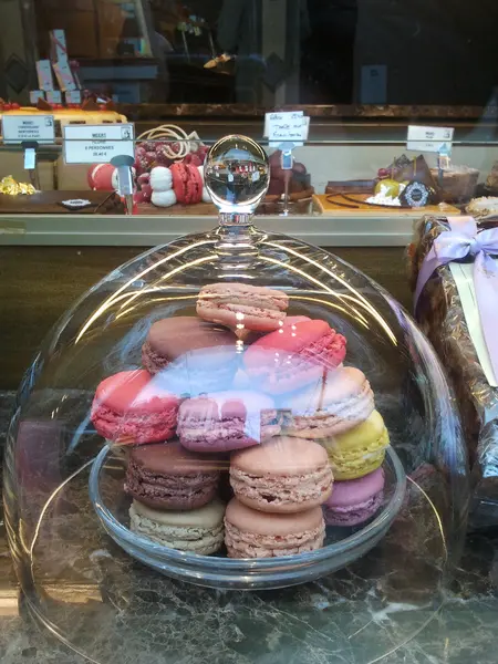 Ein Foto von französischen Macarons unter einer Glashaube.
