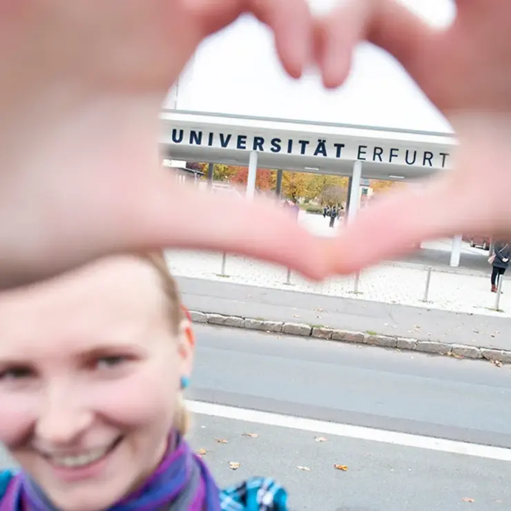 Eine Studentin steht am Eingang zur Universität Erfurt