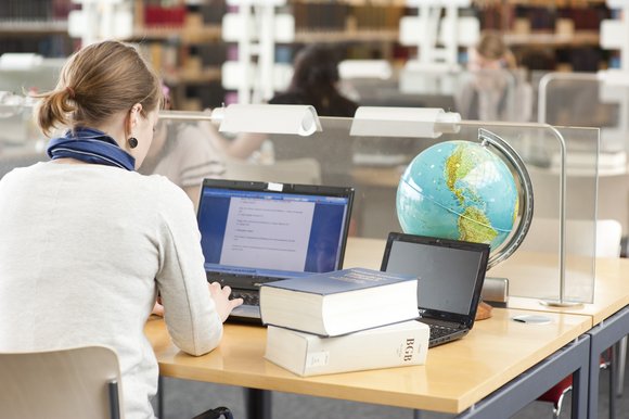 student on desk in the library with a globe