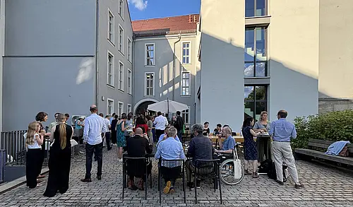 Menschen im Hof des FZG, stehend und an Tischen