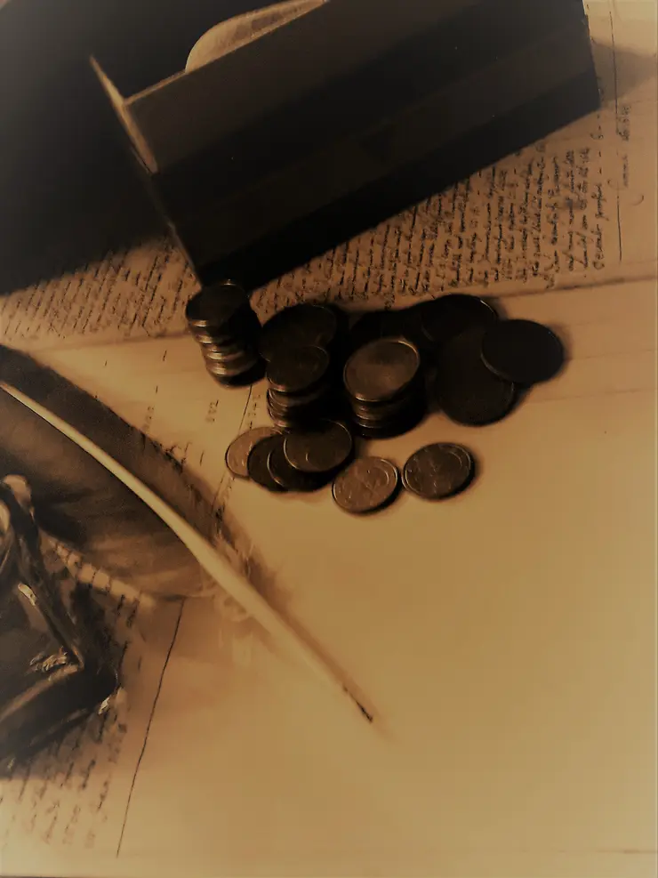 Arbeitsplatz mit Feder, Tinte und Münzen