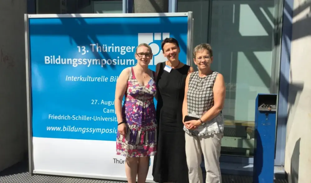 Das Team der Lernwerkstatt vor einem Schild zum 13. Thüringer Bildungssymposium in Jena