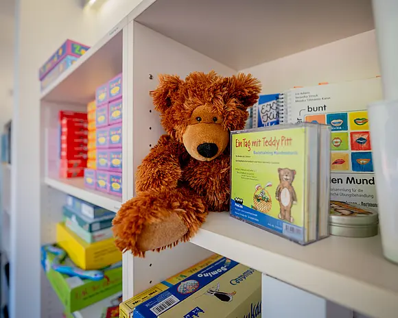 Spiele und Plüschtiere in einem weißen Regal