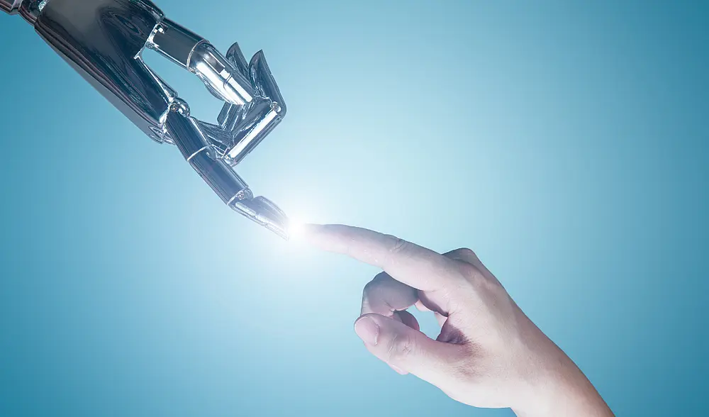 Die Zeigefinger einer Roboterhand und einer menschlichen Hand berühren sich und an dem Punkt, an dem sie sich berühren erscheint ein Licht.