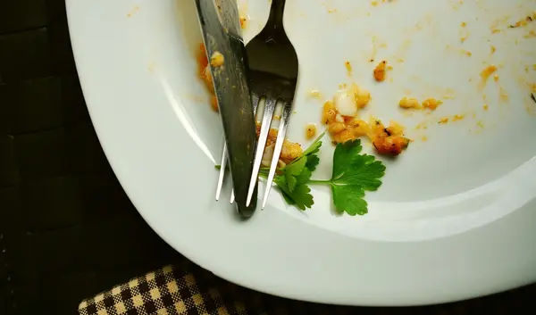 Leerer Teller mit Besteck und kleinen Essensresten (Symbolbild Fasten)