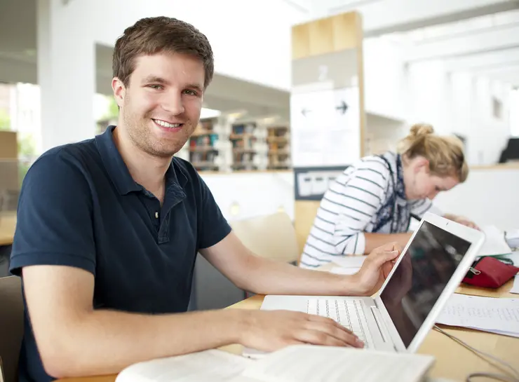 Ein Student arbeitet an einem Laptop in der Universitätsbibliotek der Universität Erfurt