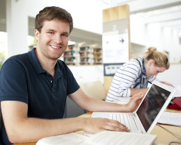 Ein Student arbeitet an einem Laptop in der Universitätsbibliotek der Universität Erfurt